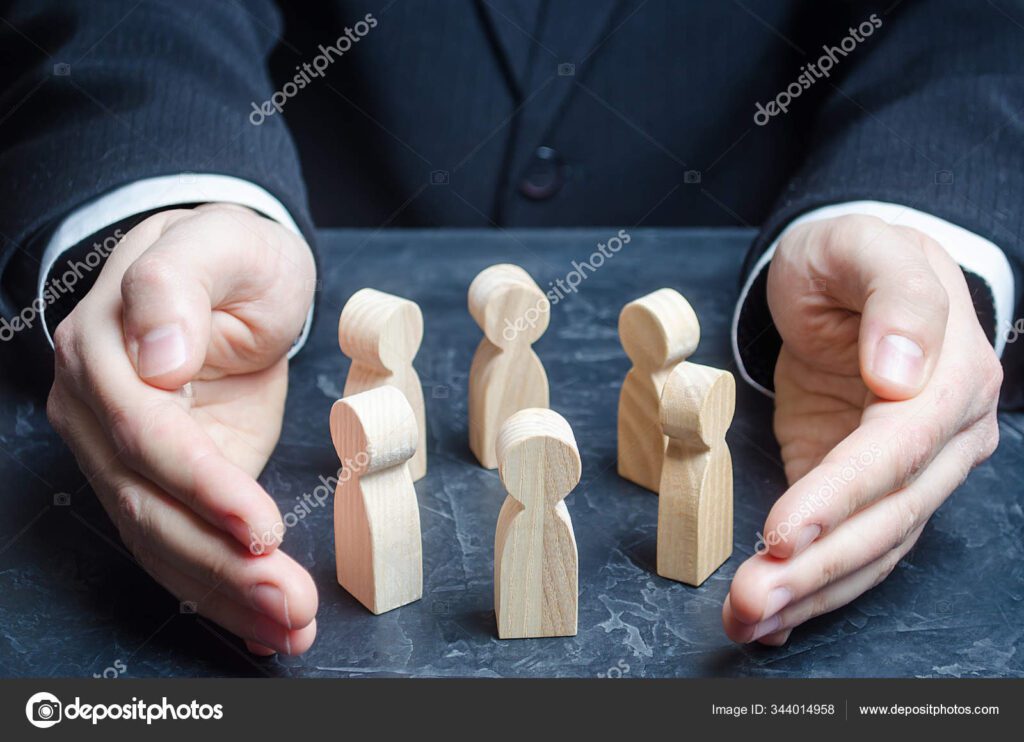 Businessman holding wooden figures in his hands stock photo.
