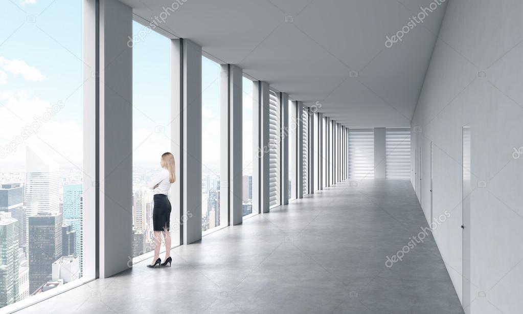 A business woman looking out of a window in a modern office building — stock photo.